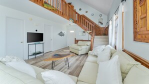 A spacious living room with a high wooden staircase, a flat-screen TV, a sofa, and a coffee table. - 7557-Turtle's Pace - Avon Canalfront Retreat With Private Dock (Avon)