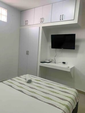 A bedroom with a bed, a TV mounted on the wall, and a wardrobe. - Ground Floor 3 Bedrm/ Getsemani_102 (Cartagena de Indias)