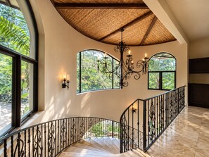 A spacious interior with a curved staircase, large windows, and a decorative chandelier.