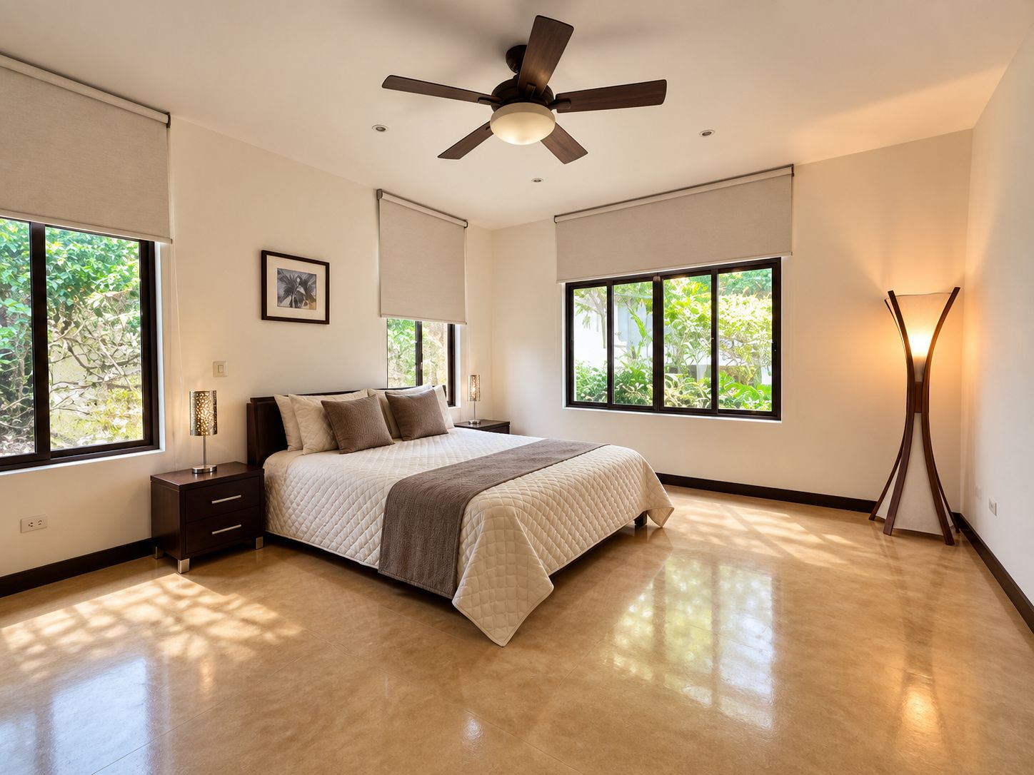 A bedroom with a bed, nightstands, a ceiling fan, large windows, and a floor lamp.