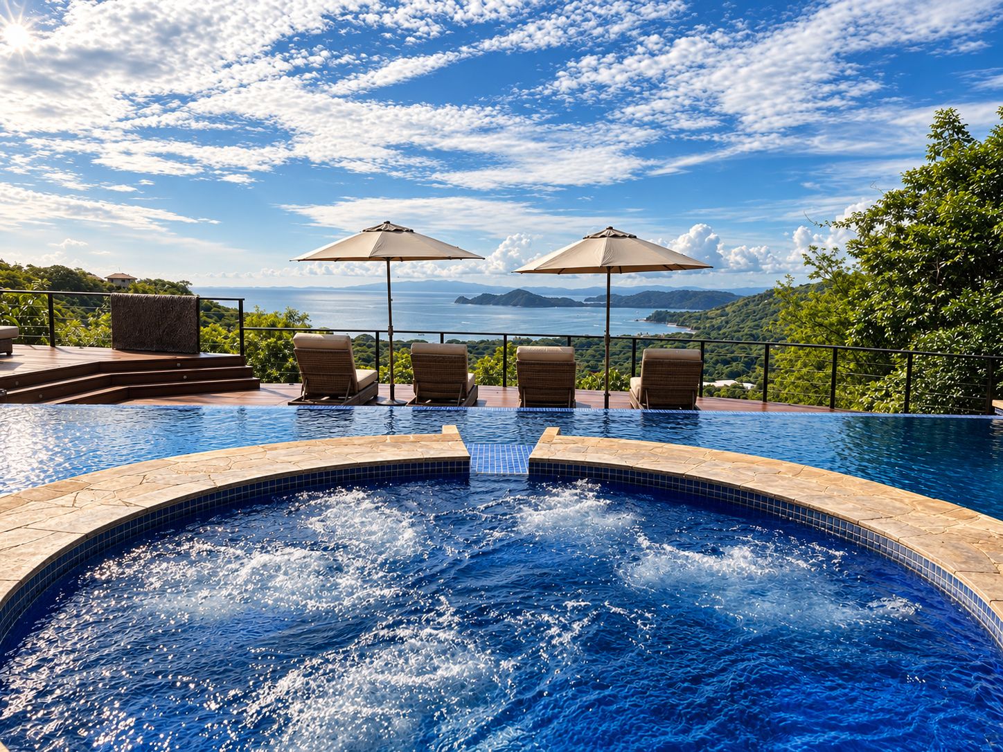 A swimming pool with a view of the sea and mountains, surrounded by lounge chairs and umbrellas.