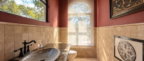 A bathroom with a large window, a sink, and a toilet.