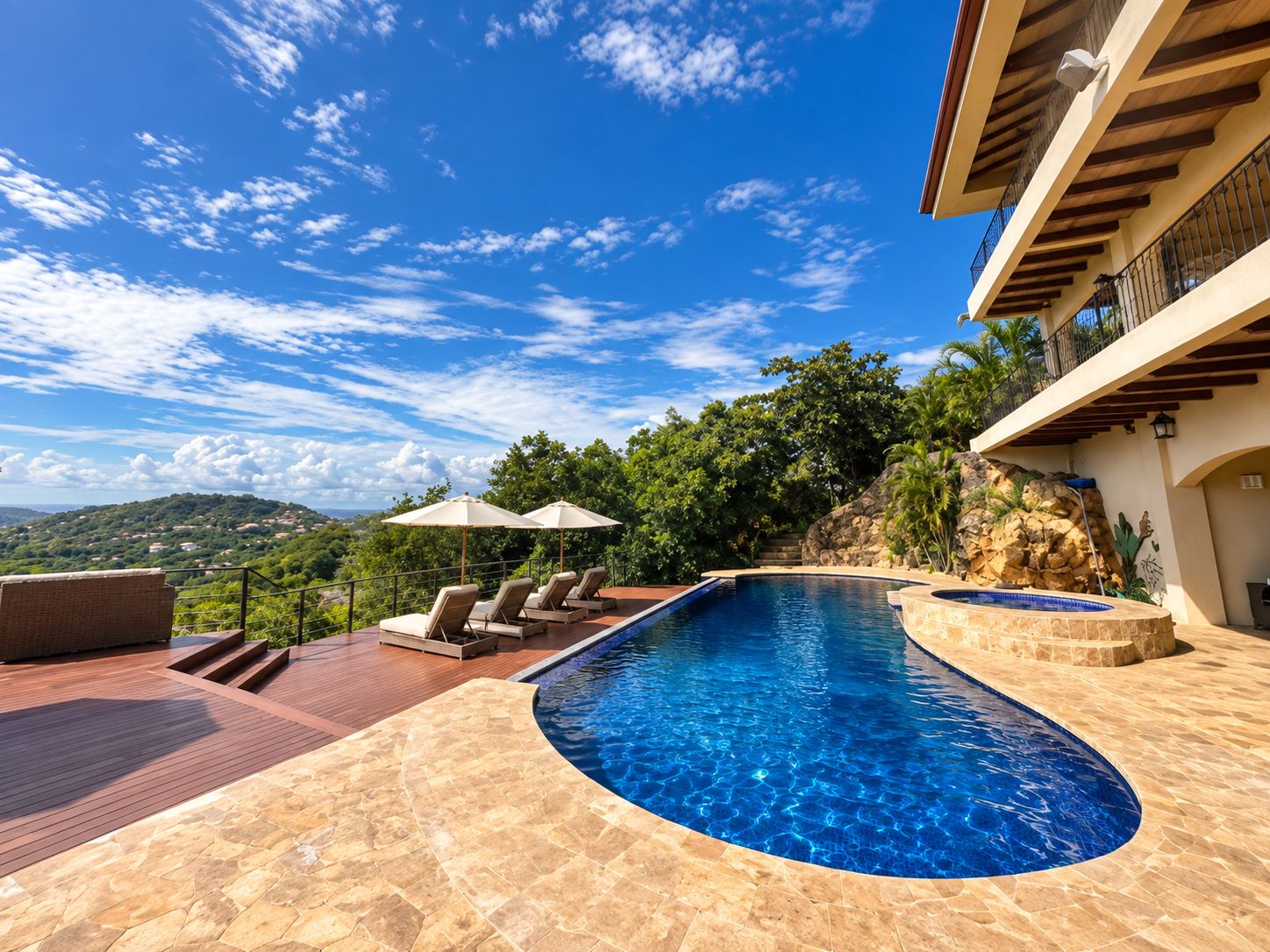 A swimming pool with a curved edge, surrounded by a wooden deck and stone tiles.