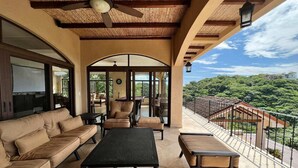 A spacious balcony with a view of lush greenery, furnished with a sofa set, a table, and chairs. - Stunning Ocean View Chateau - Experience it All (Playa Hermosa, Sardinal)