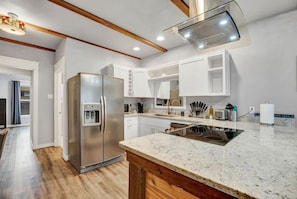 Una cocina moderna con refrigerador de acero inoxidable, horno empotrado y encimera de granito.