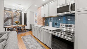 A modern kitchen with stainless steel appliances, white cabinetry, and a blue-tiled backsplash. - 8BR/7BA Mansion · Sleeps 28 · Shaw Metro (Washington)