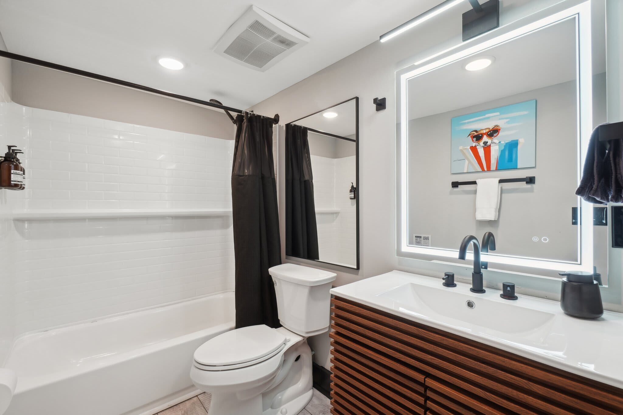 A modern bathroom with a bathtub, toilet, and vanity.