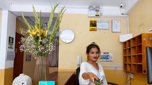 A reception desk with a vase of flowers, a clock, and a sign indicating emergency lighting. - Mariterra Host (Puerto Inca)