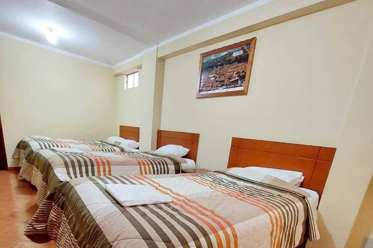 A hotel room with four beds, each with striped bedding and wooden headboards.