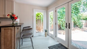 Una cucina moderna con un angolo bar, una porta scorrevole in vetro che dà su un giardino e una piccola pianta in vaso sul bancone.