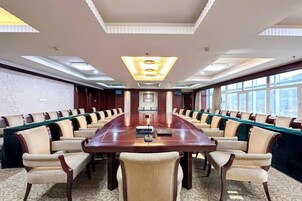 Un salón de conferencias con una larga mesa, varias sillas y vistas a la ciudad a través de amplios ventanales.