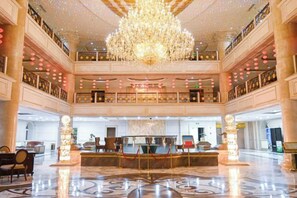 Un vaste hall d’entrée agrémenté d’un grand lustre, d’un comptoir de réception et d’un plafond haut.