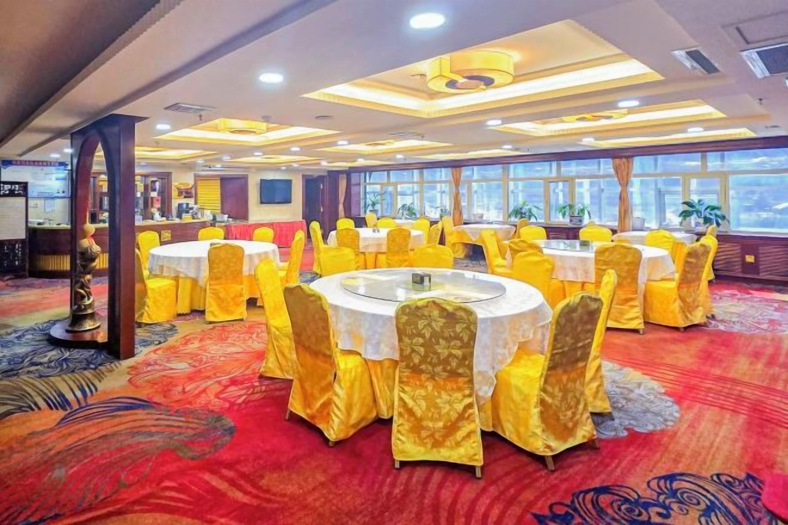 Un salón de banquetes con mesas redondas, sillas amarillas y una alfombra roja.
