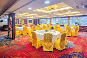 Un salón de banquetes con mesas redondas, sillas amarillas y una alfombra roja.