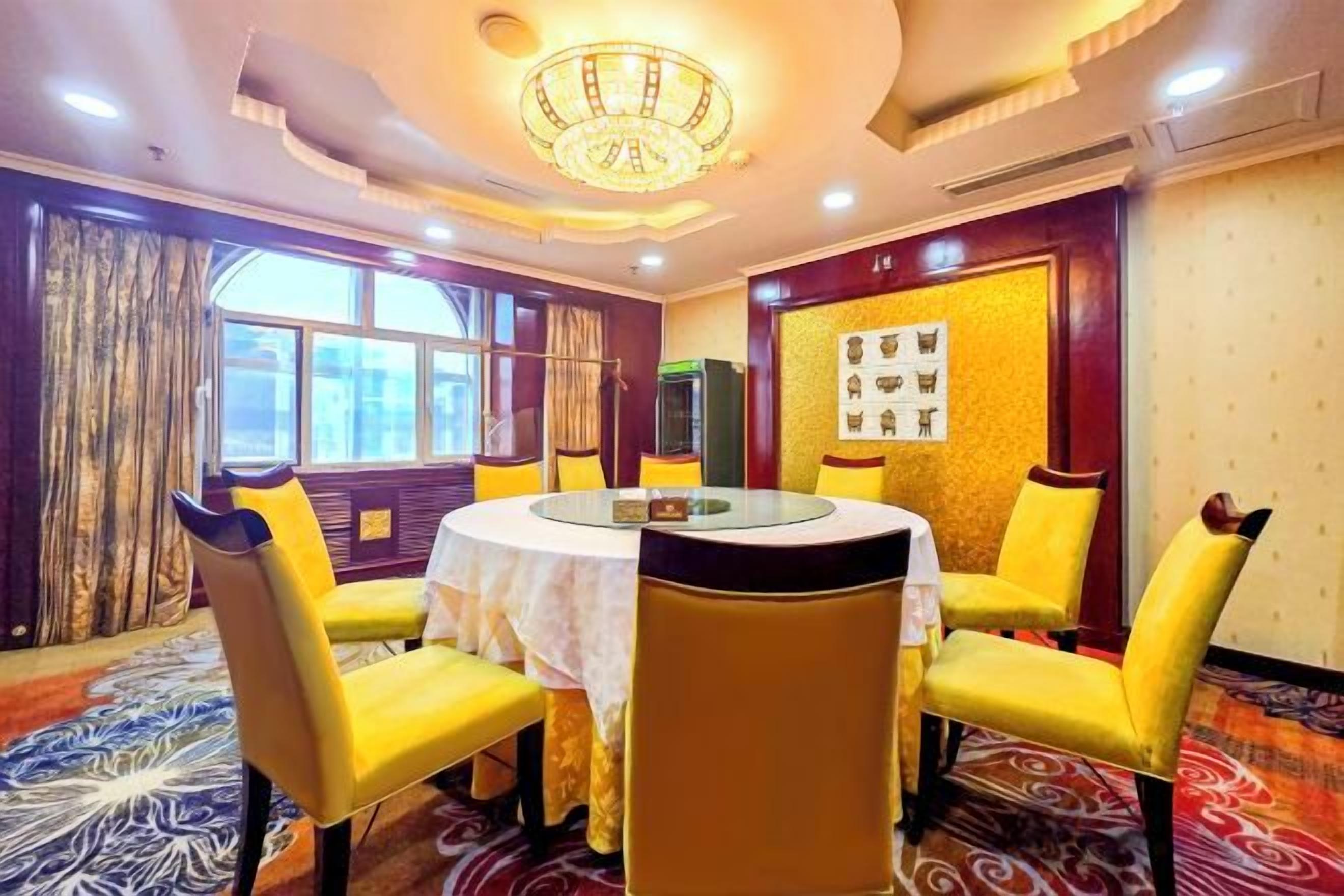 A conference room with a round table, yellow chairs, and a chandelier.