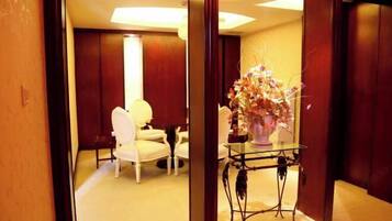 Ein Hotelzimmer mit Sitzecke, einem Glastisch mit Blumenvase und Holzvertäfelung.