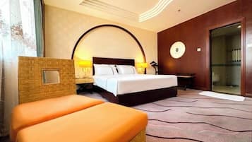 A hotel room with a bed, a small table, a chair, a mirror, and a large window with curtains.