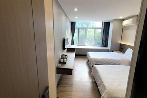 A hotel room with two beds, a TV, a window with curtains, and a small table with a kettle. - Shujie Hotel (Fuzhou)