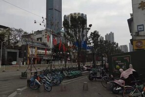 Un carrer amb bicicletes aparcades al costat del vorar i un edifici amb un rètol, amb una construcció alta al fons.