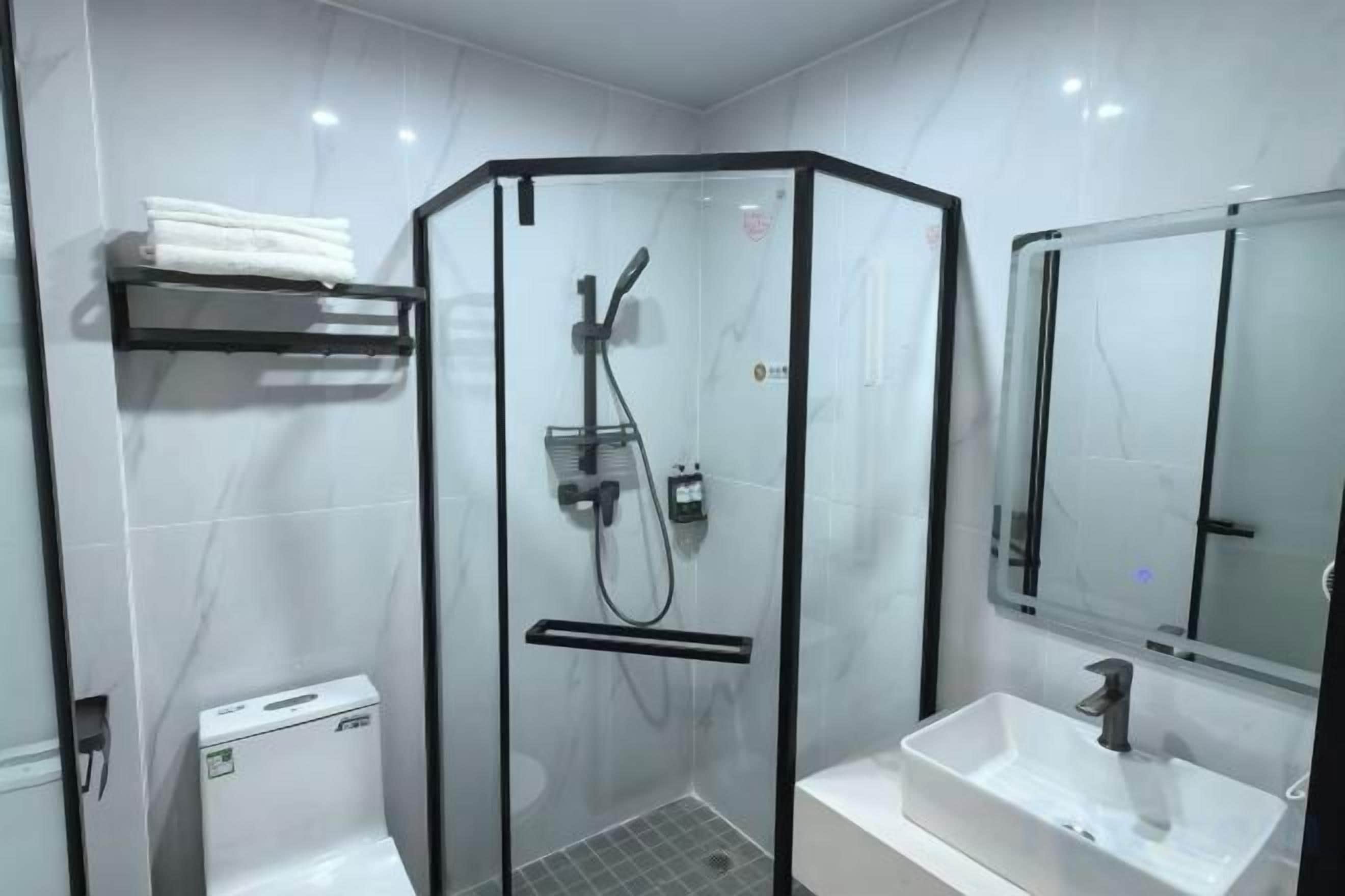A modern bathroom with a glass-enclosed shower, a white sink, and a mirror.