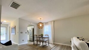 A spacious living room with a dining area, hardwood flooring, and a modern ceiling light fixture.