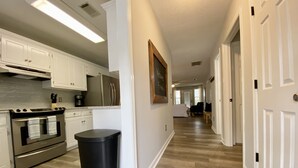 A kitchen with white cabinets, stainless steel appliances, and a black trash can.