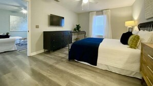 A bedroom with a bed, a dresser, a television, and a ceiling fan.