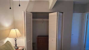 Une chambre à coucher comprenant un lit, une table de chevet avec une lampe, une commode et un placard avec des portes coulissantes.