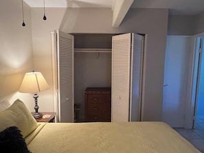 Un dormitorio con cama, mesita de noche con lámpara, cómoda y armario con puertas correderas.