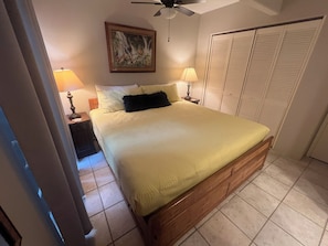 Ein Schlafzimmer mit einem Bett, Nachttischlampen, einem Deckenventilator, einem Gemälde und einem Kleiderschrank.