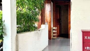 A narrow corridor with a wooden door at the end, a small table, and a red cabinet with text.