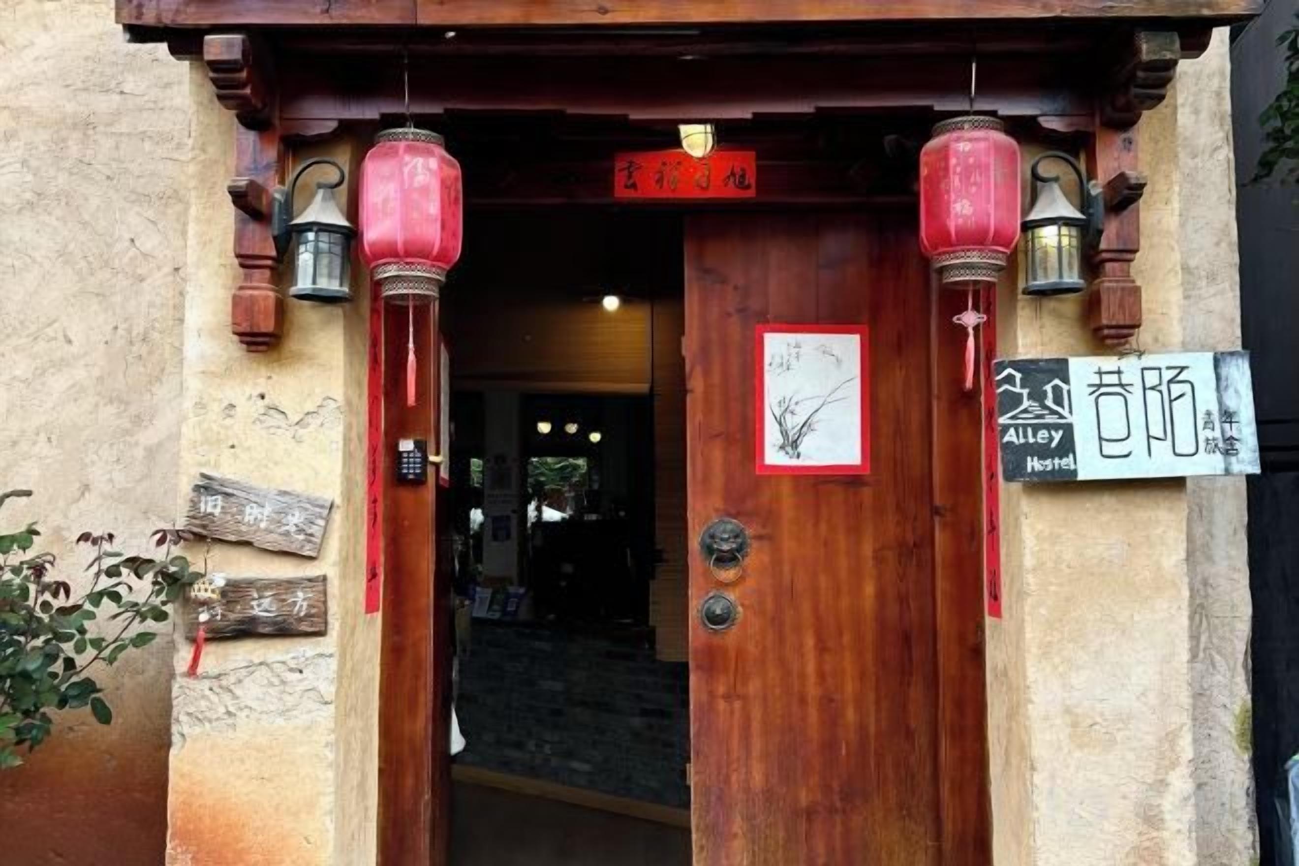 A wooden entrance with traditional lanterns, a sign indicating a hotel, and a visible door handle.