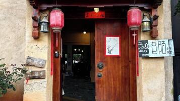 A wooden entrance with traditional lanterns, a sign indicating a hotel, and a visible door handle.