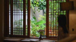Quarto com janela que oferece vista de um jardim através de grades de metal.