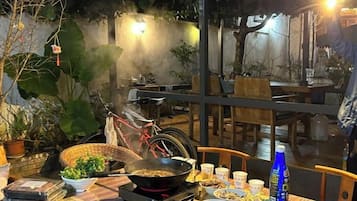 A dining table with food, a bicycle, and a potted plant.