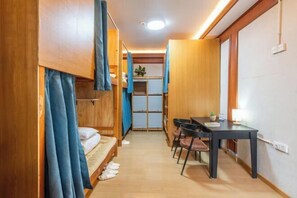 Una habitación pequeña con literas, una mesa y sillas.