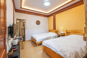 Habitación de hotel con dos camas de madera, un escritorio con silla, un televisor y un espejo montado en la pared.
