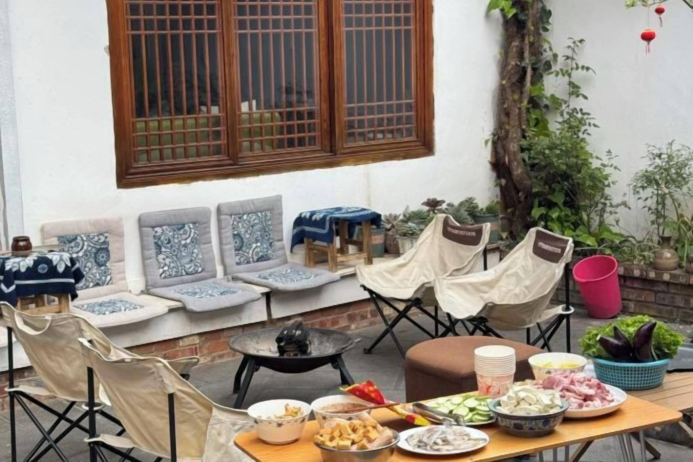 An outdoor dining area with a table set for a meal, surrounded by chairs and a sofa.