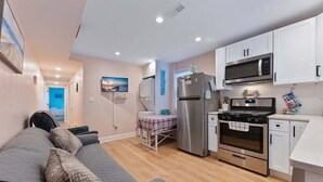 Un espacio habitable compacto con kitchenette, un sofá, una mesa de comedor y vistas al exterior.