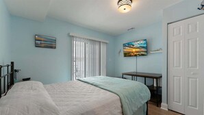 Un dormitorio con cama, mesita de noche, ventana con persianas y puerta.