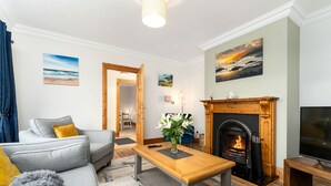 Una sala de estar con un sofá gris, una mesa de centro de madera, una chimenea y un televisor.
