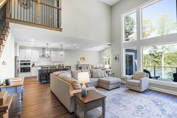 A spacious living area with a kitchen, dining area, and a large window overlooking a natural landscape.