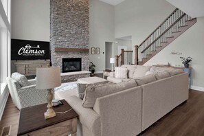 A living room with a stone fireplace, a sofa, a coffee table, and a TV.