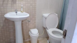 A bathroom with a pedestal sink, toilet, and a trash bin. - Lodging near mountains (El Valle de Antón)