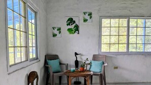 A room with two chairs, a small table, and a window. - Lodging near mountains (El Valle de Antón)