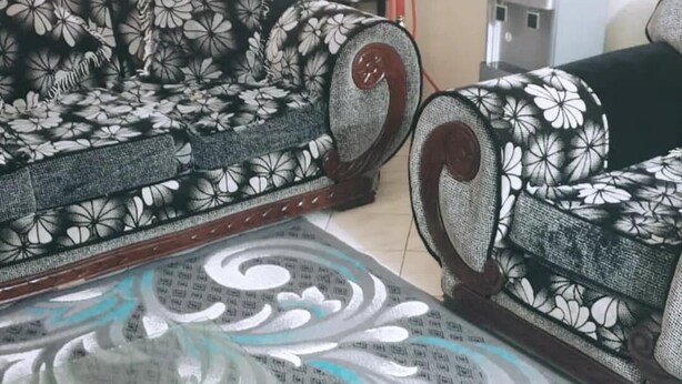 A living room with patterned sofas, a glass coffee table, and a water dispenser.