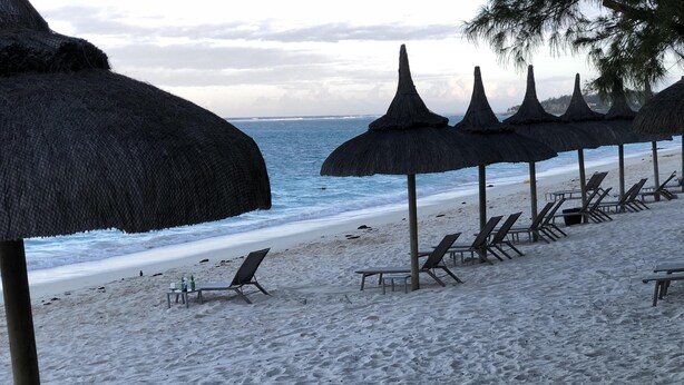 A beach with thatched umbrellas and lounge chairs. - Sugareef 3-Bed Apartment in Flic en Flac (Flic en Flac)