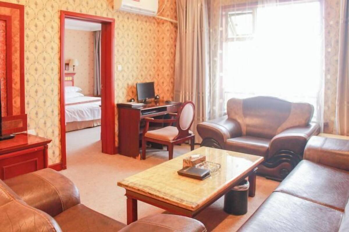 A hotel room with a bed, a desk, a leather sofa, and a coffee table.