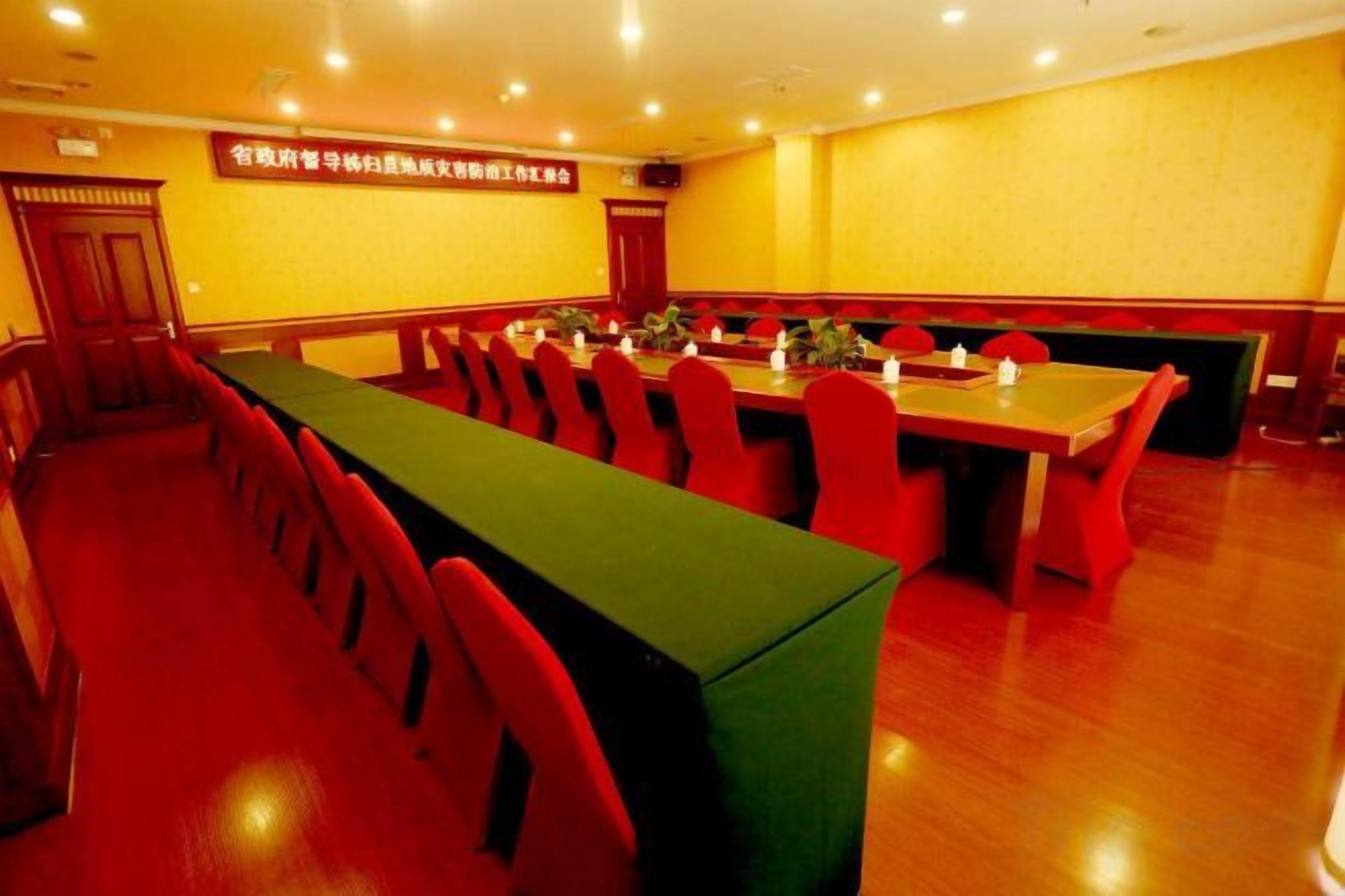 A conference room with a long table and chairs, a podium, and a banner on the wall.