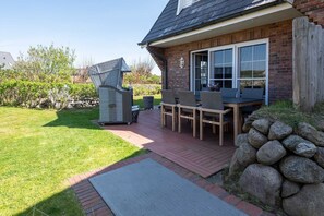 A patio with a grill, outdoor seating, and a stone wall.